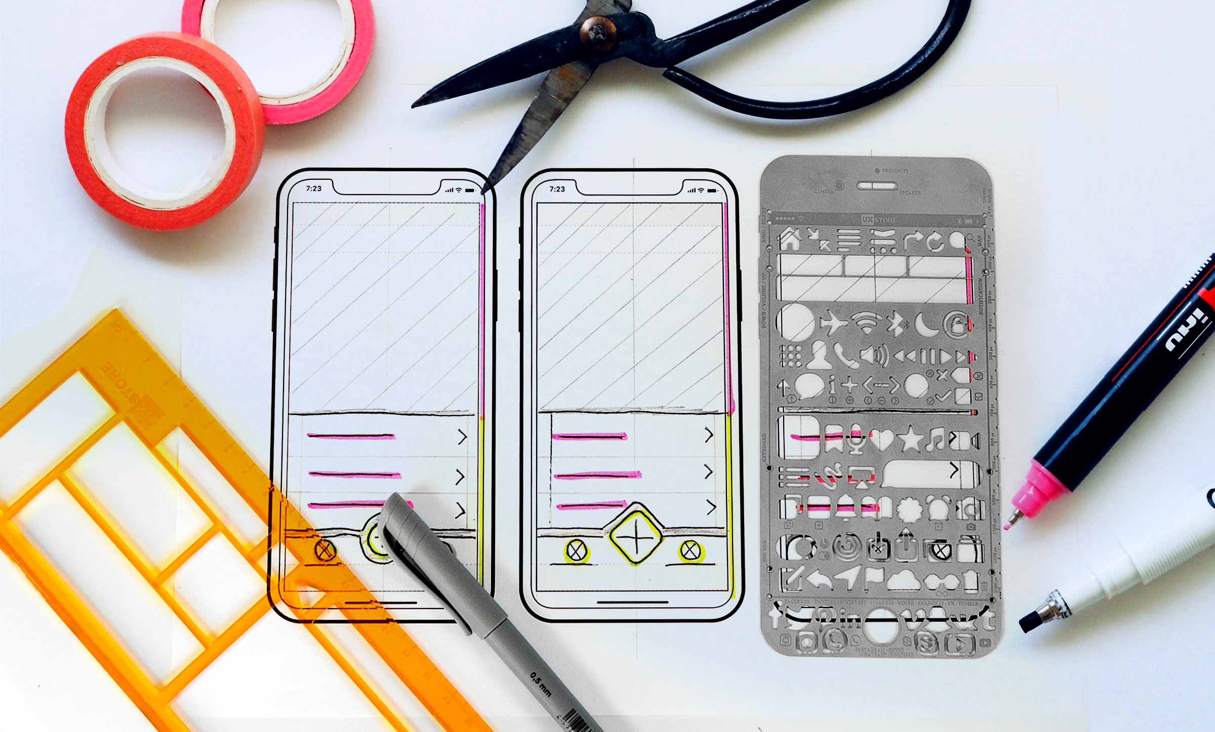 Three hand drawn phones, the third with a stencil of commonly used symbols laying over it, sit on a white background surrounded by school supplies, such as a ruler, scissors, pens, and rolls of pink tape.